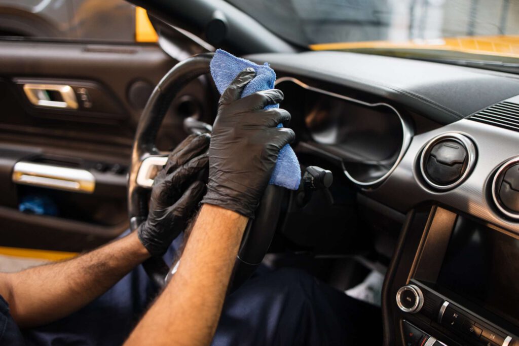 nahaufnahme-der-haende-eines-arbeiters-bei-der-autoaufbereitung-mit-schutzhandschuhen